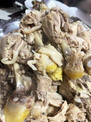 A close-up of multiple boiled chicken pieces served on a plate, showcasing their texture and preparation style.