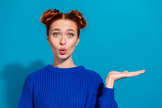 Portrait of a young woman in a blue sweater gesturing with an expressive face against a vibrant blue background