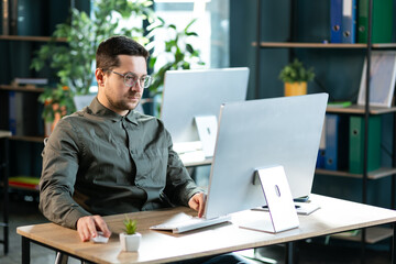 Portrait shot of the young man working on personal computer in cozy office.