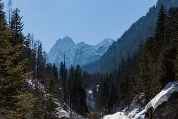 vista dettagliata di un ambiente di montagna con ripidi pendii e catene montuose nel nord Italia, sotto un cielo sereno, di mattina, in inverno