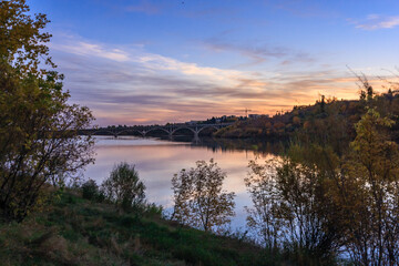 A beautiful sunset over a river with a bridge in the background