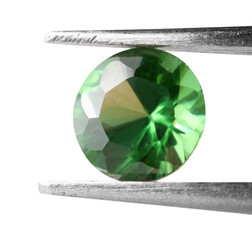 Tweezers with shiny green gemstone isolated on white