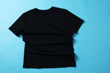 One black t-shirt on light blue background, top view
