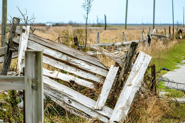 Broken fence with sections damaged by strong winds, showcasing structural destruction and vulnerability