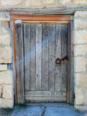 There is a beautifully crafted wooden door set into a sturdy stone wall, and it features a key resting on its surface, suggesting a sense of mystery and potential security