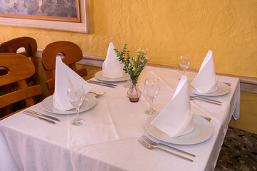 Elegant Table Setting with Fresh Flowers and Napkins in a Cozy Mediterranean Restaurant