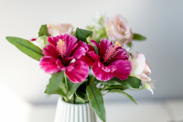 Close-up of Vibrant Pink Artificial Hibiscus Flowers in a White Ceramic Vase