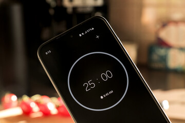 A phone with a black and white 25-minute timer for recipe cooking in kitchen with fresh food...