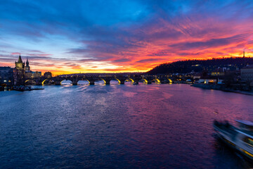 Fiery sunset over historic Prague - breathtaking sunset with the iconic Charles Bridge and Vltava River illuminated in vibrant shades of orange, pink and purple.