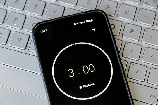 A phone with a black and white 3-minute timer to study with pomodoro method on laptop keyboard, study business background