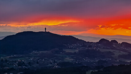 Dramatic sunrise seen from top of Kathreinkogel overlooking Pyramidenkogel and rolling hills of idyllic village Schiefling am See, Carinthia, Austria. Magical atmosphere in remote Austrian Alps