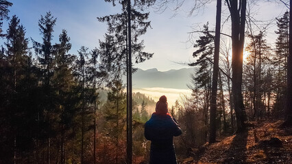 Obraz premium Active woman on top of Kathreinkogel overlooking cloud covered Rosental valley in Schiefling am See, Carinthia, Austria. Majestic mountain peaks of Karawanks, Austrian Alps. Tranquil serene atmosphere