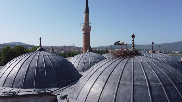 A view of the historical Eşrefoğlu Mosque and covered bazaar in Konya Beyşehir. A stork on the domes of the covered bazaar reveals the harmony of the historical structure and nature.