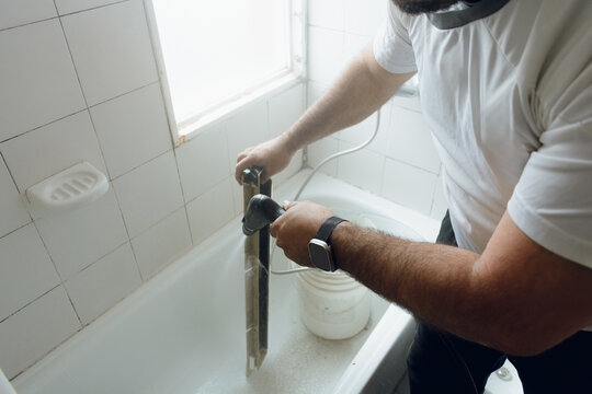 Technician man with a hydrojet cleaning dirty air conditioning parts