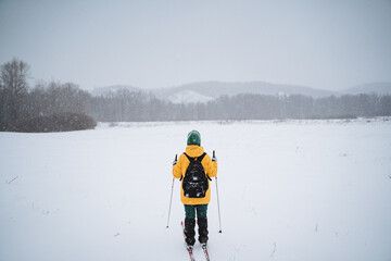 A person wearing a bright yellow jacket is joyfully skiing down a snowy slope, enjoying the winter weather and the exciting outdoor recreation that comes with this beautiful season