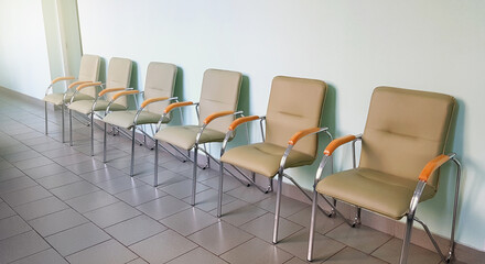 Row of modern chairs with chrome frames and padded seats in a hospital waiting area, mobile photo