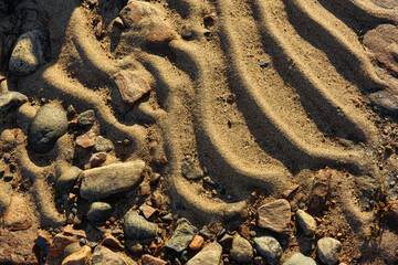 A fragment of a sandy beach with multi-colored stones