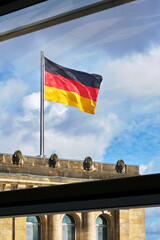 German Flag Sunshine and Clouds. German flag, through a window, waving against the sky in the sun. 

