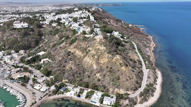 Breathtaking aerial view of Sidi Bou Said, Tunisia, showcasing its iconic blue and white architecture, picturesque marina, vibrant streets, and stunning Mediterranean coastline under a clear sunny sky