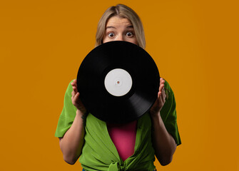 Pretty woman with vinyl record disc on yellow. Hobby, music lover, collection, nostalgia lifestyle.