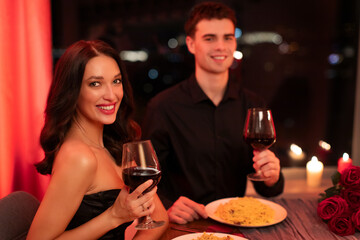 Happy European couple celebrating anniversary or Valentine's day together, sitting at table in restaurant, drinking wine
