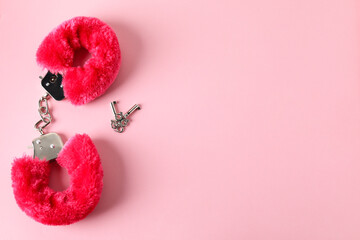 Fluffy handcuffs and keys on pink background, flat lay. Space for text
