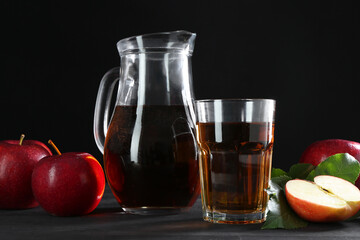 Tasty fresh apple juice and fruits on black wooden table