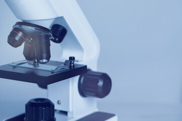 Science. Microscope with glass slide on light grey background, closeup. Space for text