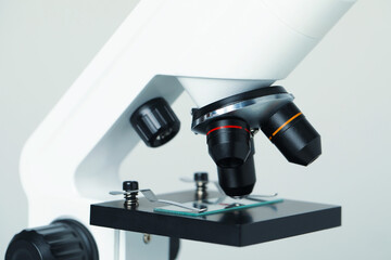 Science. Microscope with glass slide on light grey background, closeup