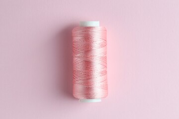 Spool of sewing thread on pink background, top view