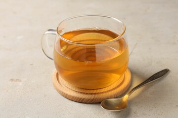 Refreshing green tea in cup and spoon on light textured table, closeup