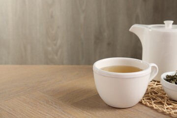 Refreshing green tea in cup on wooden table, closeup. Space for text