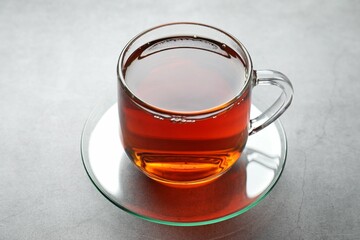 Refreshing black tea in cup on grey textured table, closeup