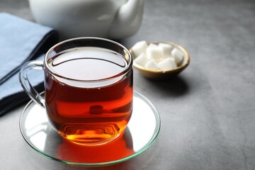 Refreshing black tea in cup on grey table, closeup. Space for text