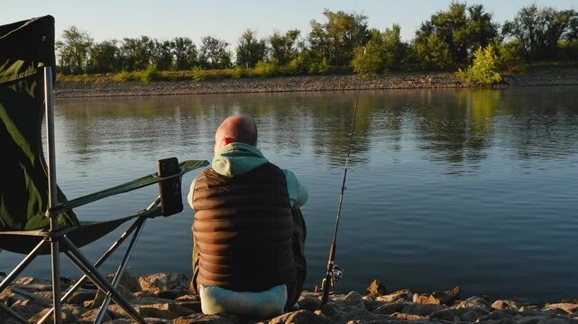 Fishing in the river. Fisherman with a fishing rod on the river bank. A man fisherman catches fish. Fishing, spinning, fish, Breg River. The concept of rural recreation
