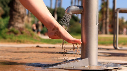 Beach shower. Girls wash their feet from sand with tap water near the beach. People wash their feet when leaving the beach. Women wash their feet close-up. Beach shower near the sea