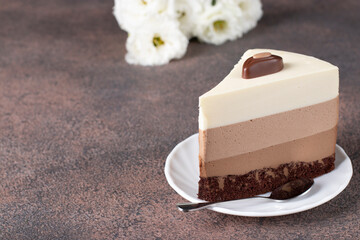 Piece of mousse cake Three chocolates on white plate