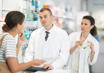 Obraz premium Two pharmacists offer a girl medicine for pain in a pharmacy