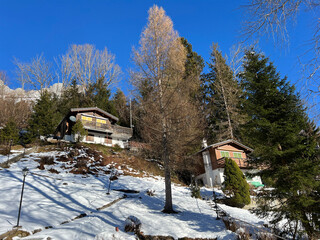 Old traditional swiss rural architecture and alpine livestock farms in the winter ambience over the Lake Walen or Lake Walenstadt (Walensee) and in Swiss Alps, Walenstadtberg - Switzerland (Schweiz)