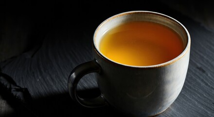 Warm cup of herbal tea on a dark wooden surface