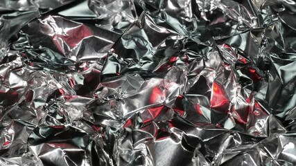 Silver metal background with red flashes. The texture of an abstract background made of crumpled aluminum foil. embossed and voluminous