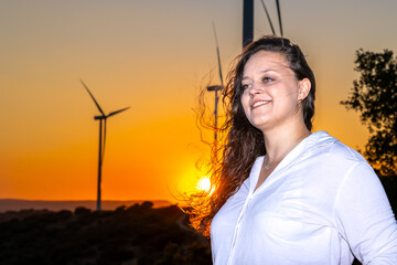 female engineer smiling at wind farm during sunset