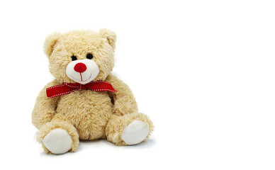 Cute teddy bear doll for babies and children. Fluffy soft stuffed toy.  isolated on white background with copy space. Beige yellow color with red nose and bow around neck.for a boy or girl child