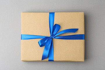 Gift box with blue bow on grey background, top view