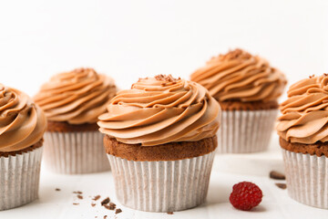 Tasty cupcakes with chocolate cream on white tiled table, closeup