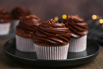 Tasty cupcakes with chocolate cream on wooden table, closeup