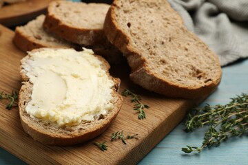 Fresh bread with butter and thyme on blue wooden table, closeup