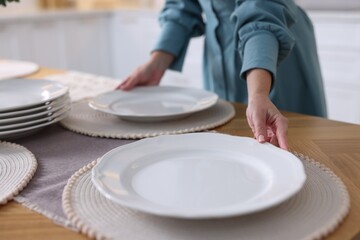 Woman setting table for dinner at home, closeup