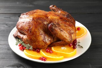 Delicious baked turkey, orange slices, cranberries and thyme on gray wooden table, closeup