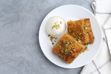 Tasty baklava with chopped nuts and scoop of ice cream on grey table, top view. Space for text